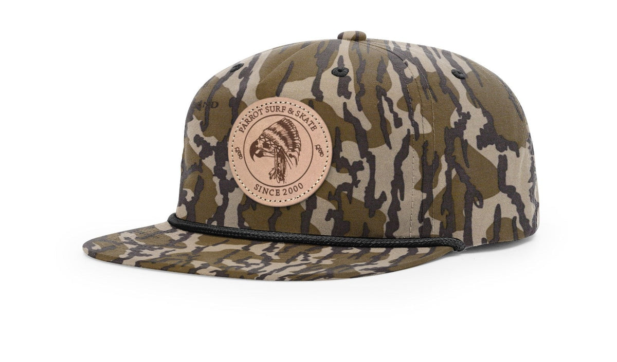 Parrot Surf & Skate 256P Indian Rope hat in Mossy Oak Bottomland with black rope and leather Indian patch, studio angle view - Parrot gear