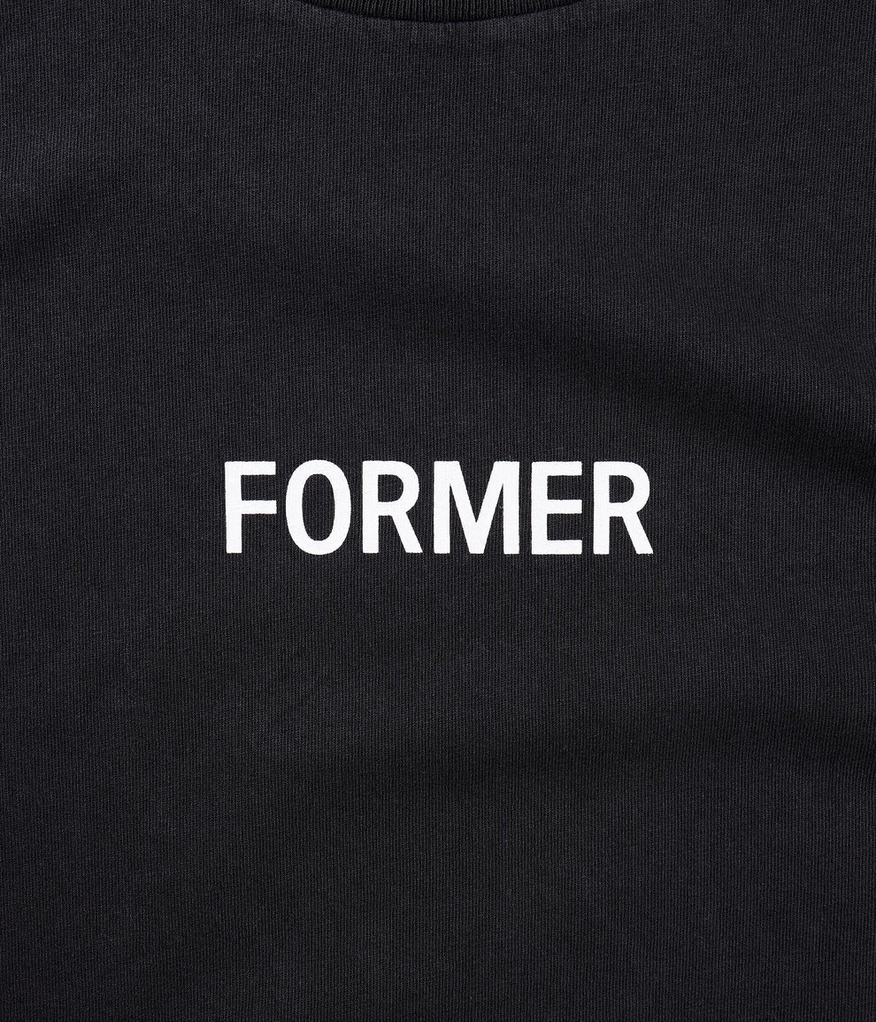 Former Legacy logo detail on washed black tee close-up