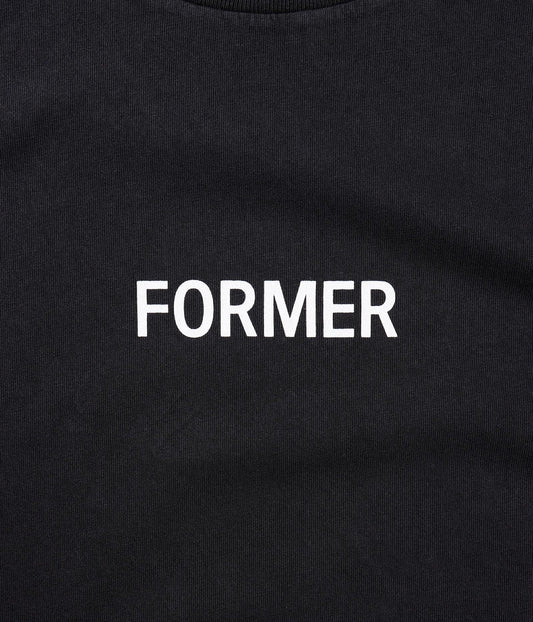 Former Legacy logo detail on washed black tee close-up